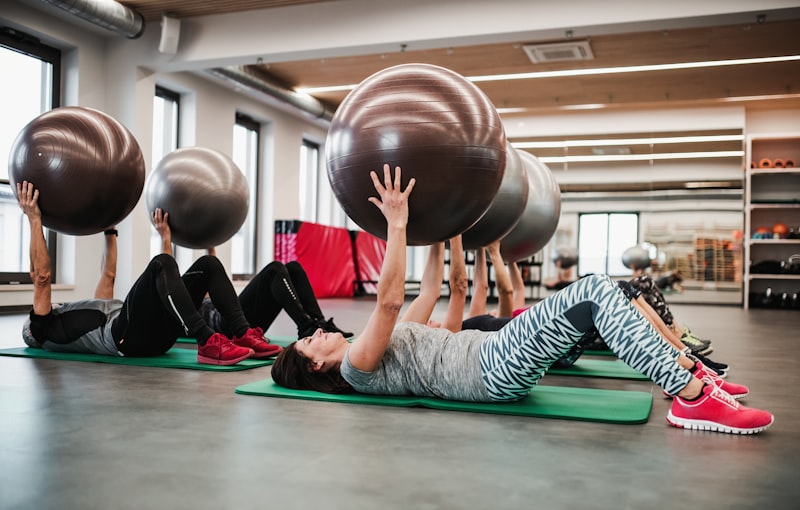 Groep senioren die oefeningen doen met fitballen in de sportschool